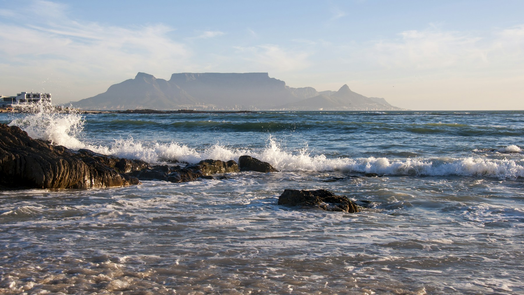 Table Mountain beyond the sea, with waves breaking over rocks in front